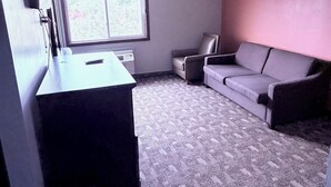 Una habitación con escritorio, sofá, ventana y radiador.