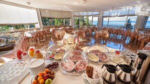 Un buffet proposant une variété de plats et un coin café, installé dans une pièce spacieuse dotée de grandes fenêtres offrant une vue sur la mer.