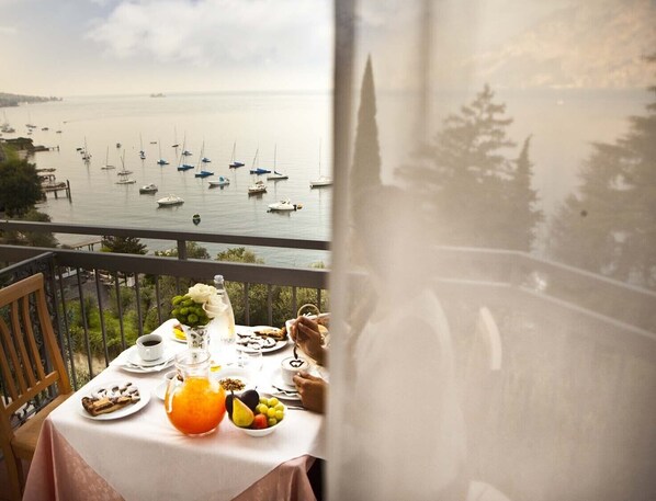 Un balcón con una mesa dispuesta para el desayuno, con vistas a un puerto deportivo lleno de barcos.