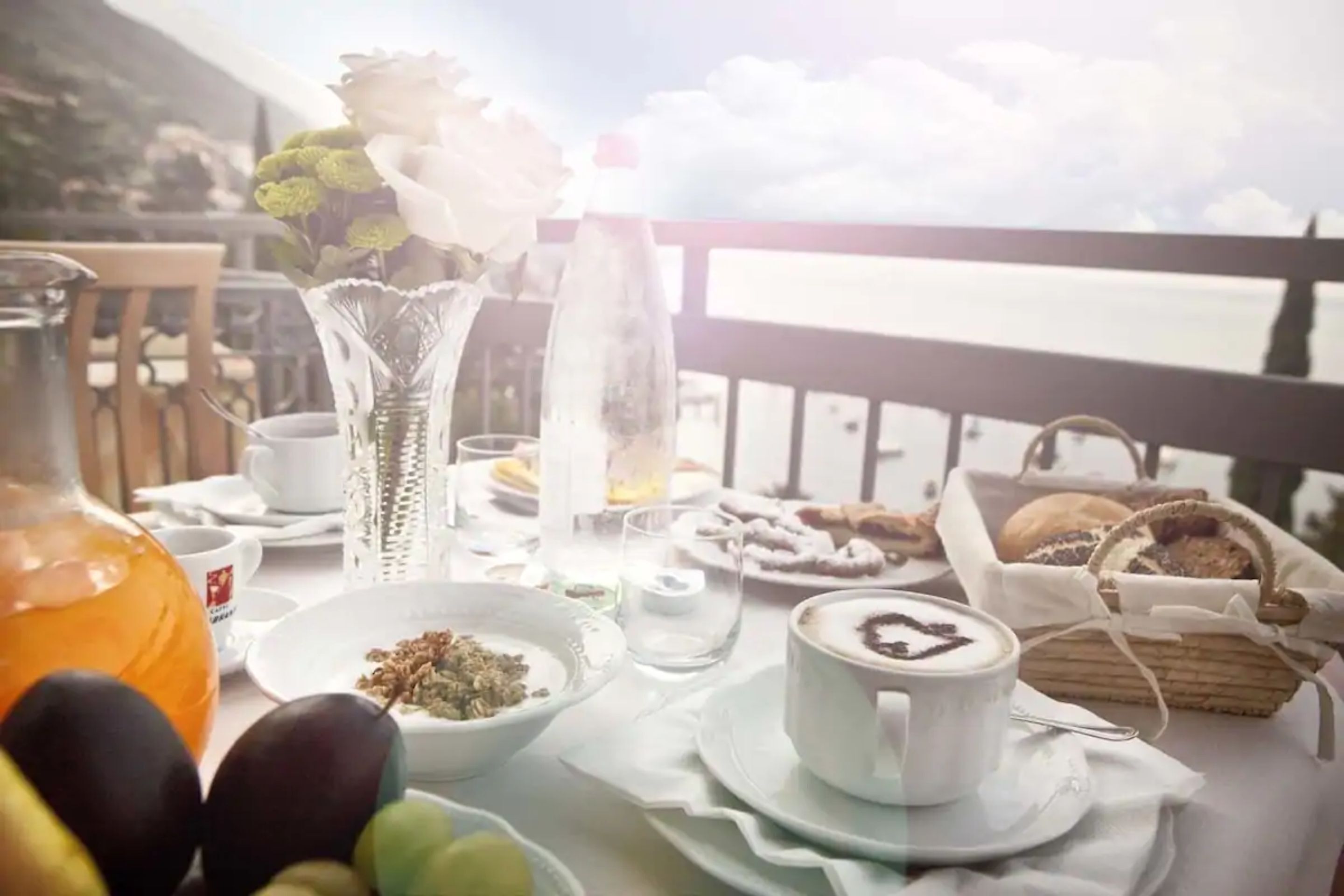 Une table mise pour le petit-déjeuner, avec une variété d’aliments, un vase rempli de fleurs et une bouteille de jus d’orange.