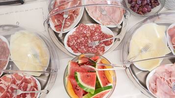 Una mesa de bufé con diversos alimentos, incluyendo carnes, quesos y frutas.