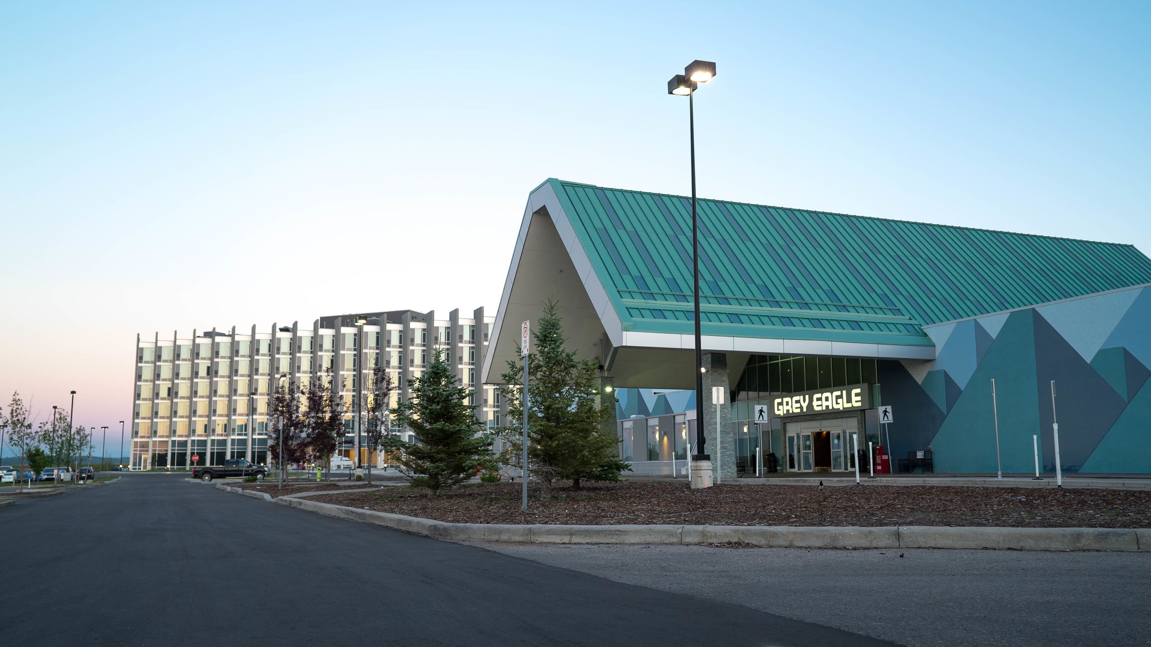 Un hotel de diseño moderno, con un llamativo letrero 'Grey Eagle', un amplio estacionamiento y una fachada geométrica singular.