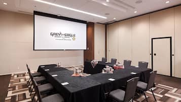 Une salle de conférence dotée d’un grand écran affichant le logo de « Grey Eagle Resort & Casino », de plusieurs tables avec des chaises et d’un tapis à motifs.