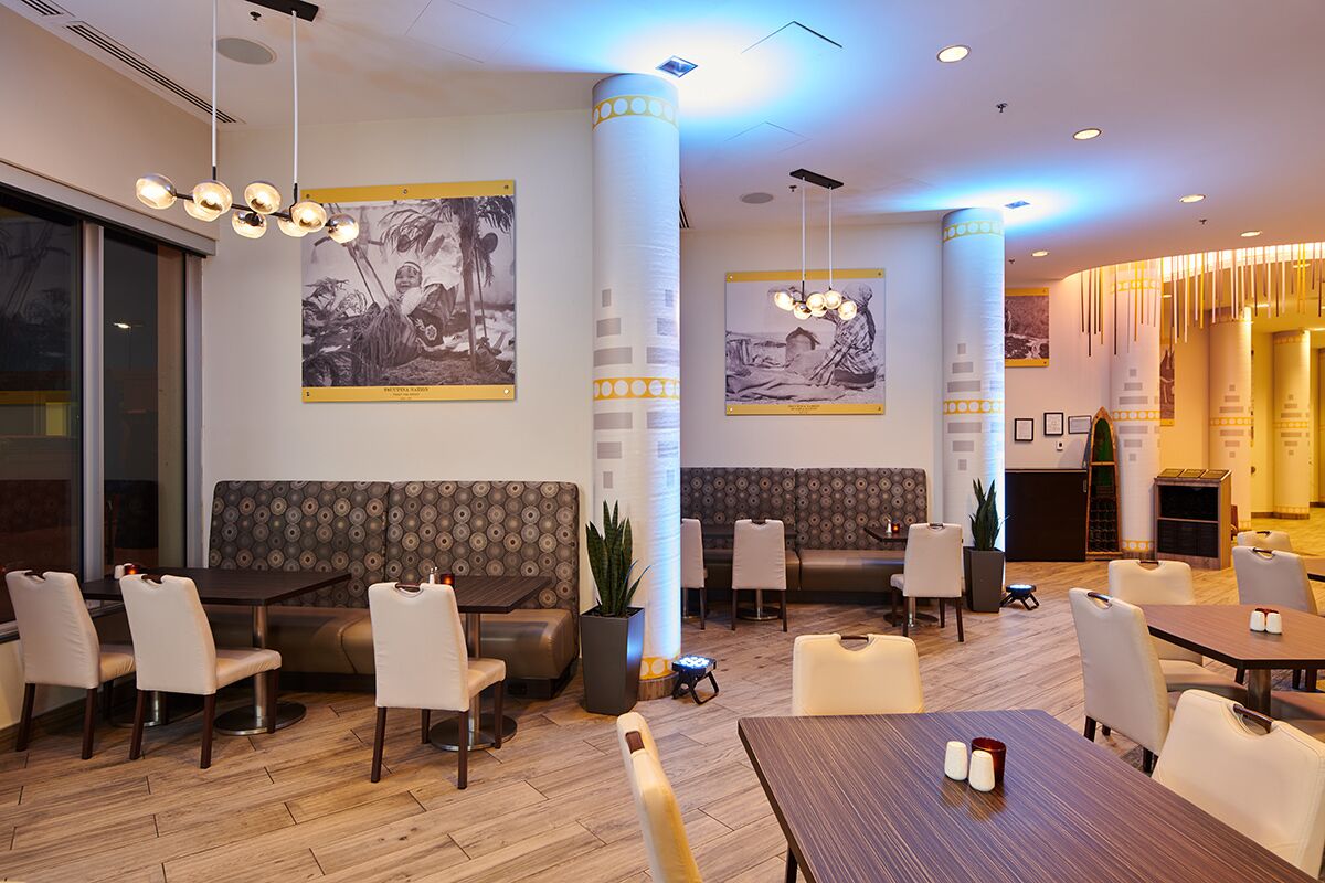 A hotel lobby with seating areas, tables, and artwork on the walls.