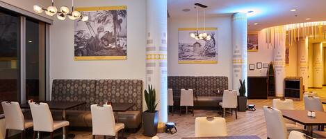 A hotel lobby with seating areas, tables, and artwork on the walls.