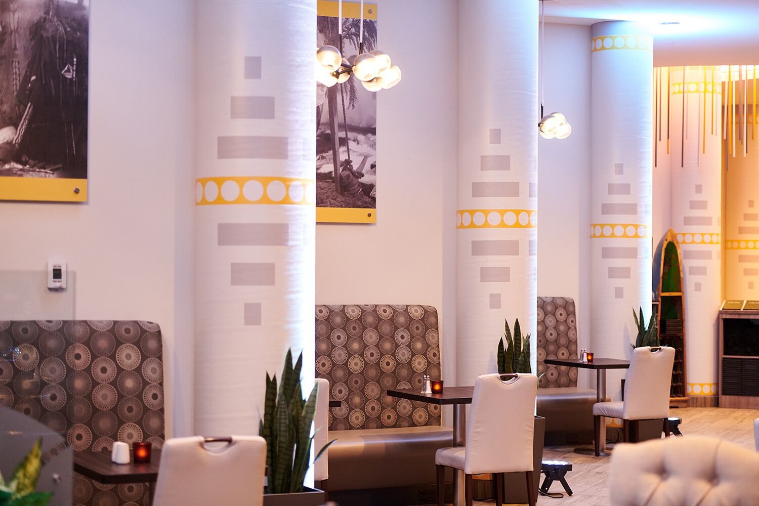 A modern lounge area with patterned sofas, a fireplace, and pendant lighting.