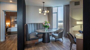 Ein Hotelzimmer mit Bett, einer Sitzecke mit Tisch, einem Schreibtisch und Blick auf eine verschneite Landschaft.