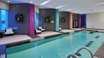 Una piscina con zona poco profunda, sillas de descanso y plantas decorativas.