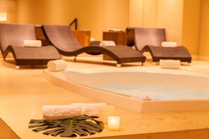 A spa area with lounge chairs, a hot tub, towels, and a candle. - Movich Buró 26 (Bogotá)