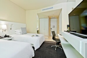 A hotel room with two beds, a desk with a flat-screen TV, a chair, and a lamp. - Movich Buró 26 (Bogotá)