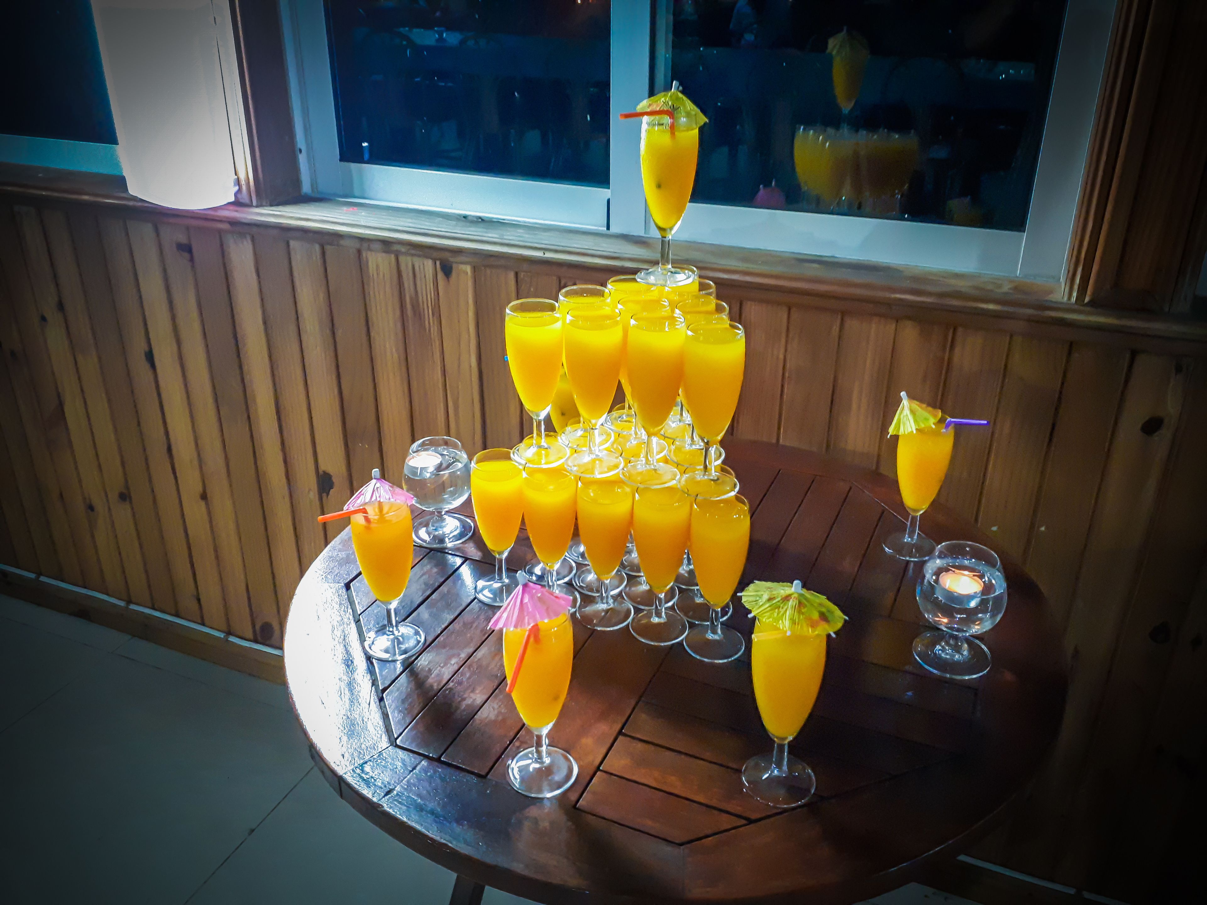 A table with multiple glasses of orange juice arranged in a pyramid shape.