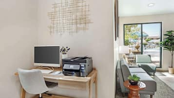 Een moderne kantoorruimte met een bureau, computer, printer en uitzicht op het terras.