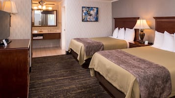 A hotel room with two beds, a bathroom, and a desk.