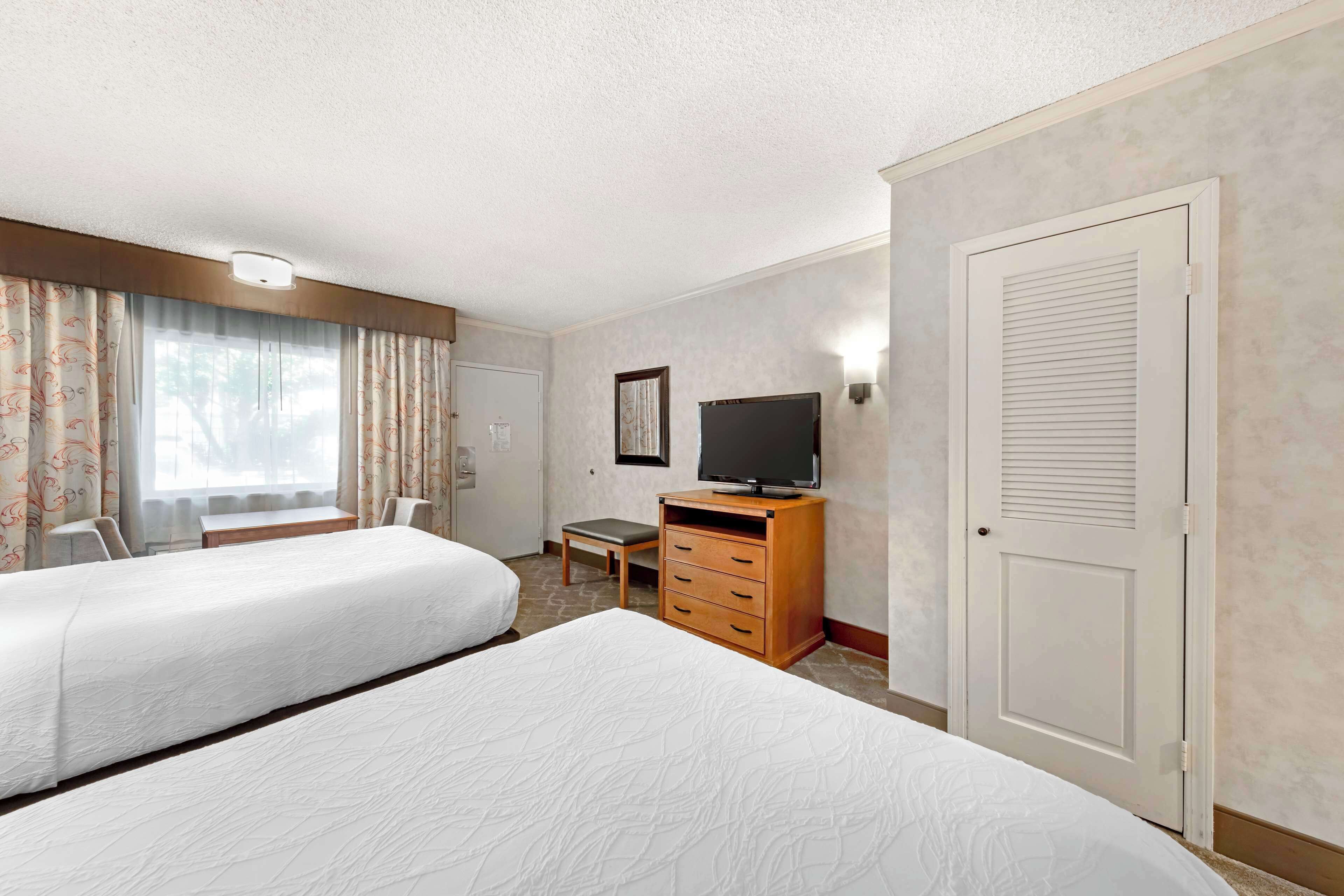 Een hotelkamer met twee bedden, een bureau, een televisie en een kledingkast.