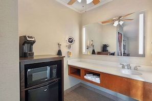 Un baño moderno con microondas integrado, tocador con lavabo y ventilador de techo.