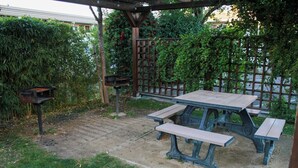 Una mesa de picnic con bancos en un jardín con una pérgola de madera.