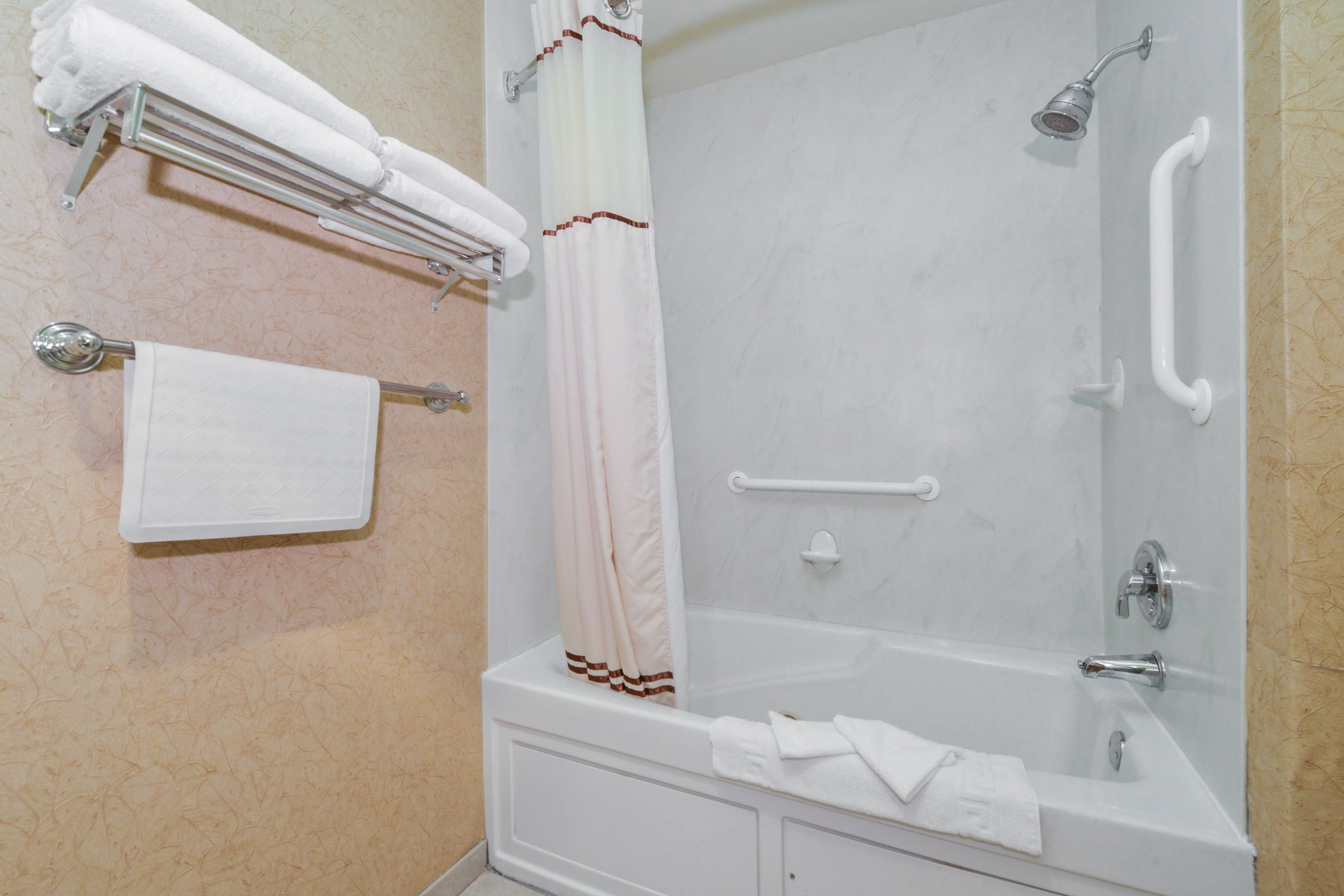 A bathroom with a bathtub, a shower, and a towel rack with towels.