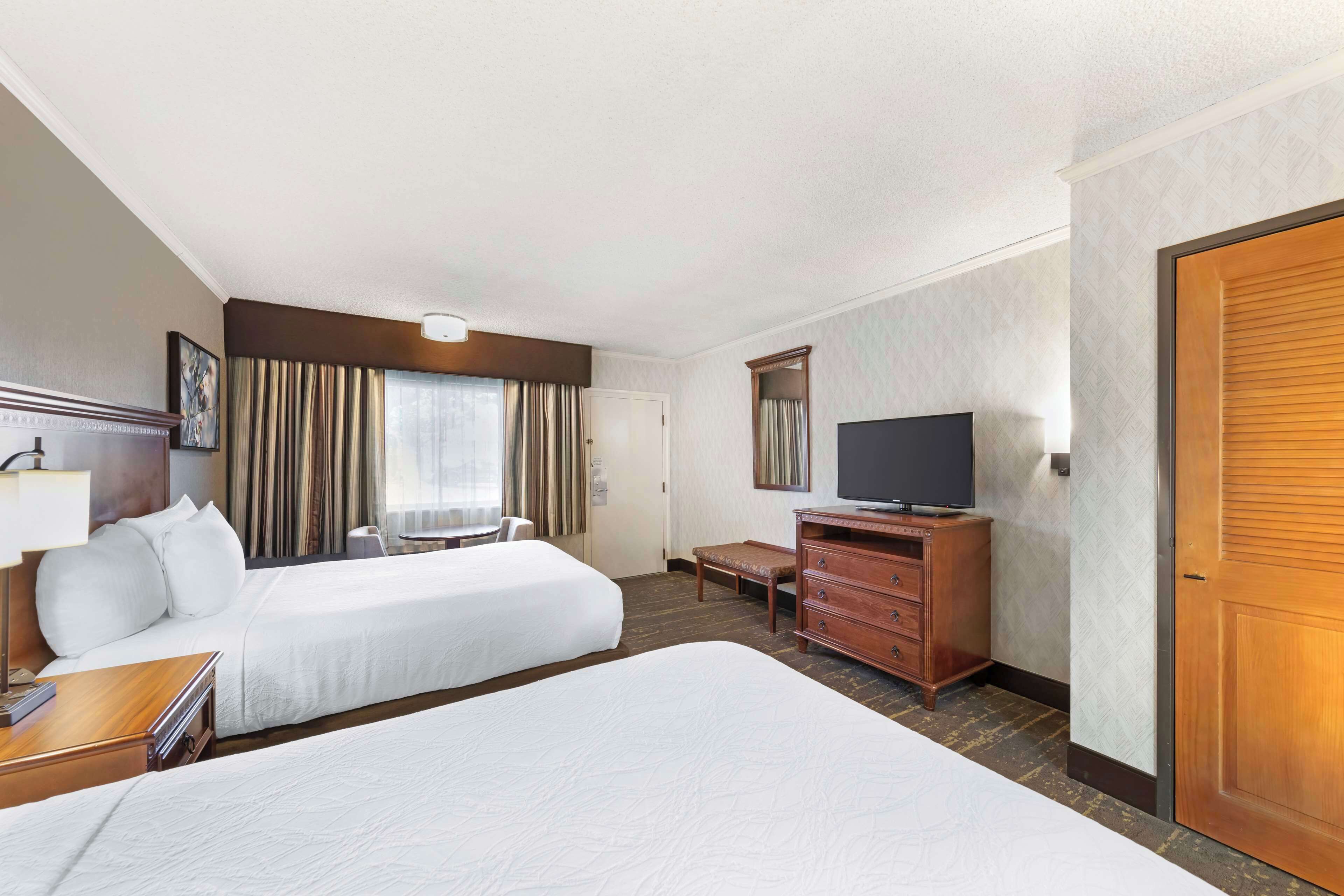 A hotel room with two beds, a TV, a desk, and a dresser.