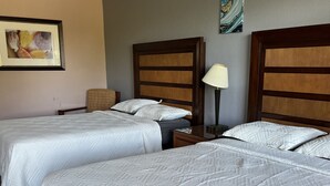 Een hotelkamer met twee bedden, een nachtkastje, een lamp en een lijst met een afbeelding aan de muur.