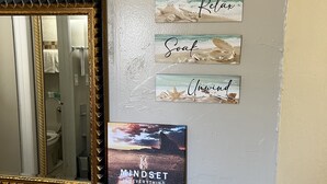 Een badkamer met een spiegel, een motiverende quote en een klein plankje met toiletartikelen.