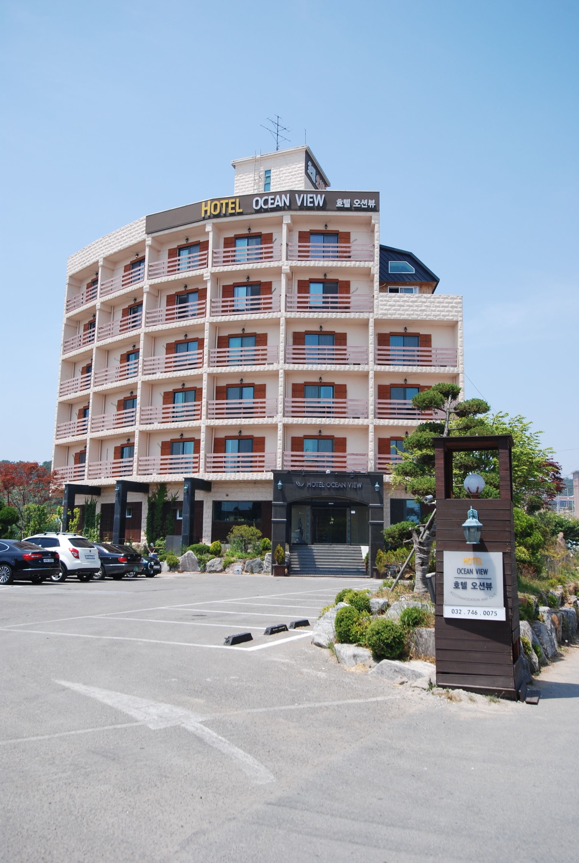 Un hotel de varios pisos llamado "Hotel Ocean View", con un diseño arquitectónico moderno, balcones y una entrada destacada.