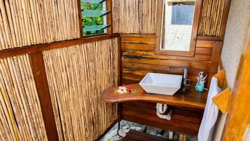 A compact bathroom with a wooden vanity, a sink, and a mirror.