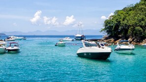Un puerto deportivo con diversas embarcaciones amarradas, agua tranquila y un paisaje montañoso al fondo.