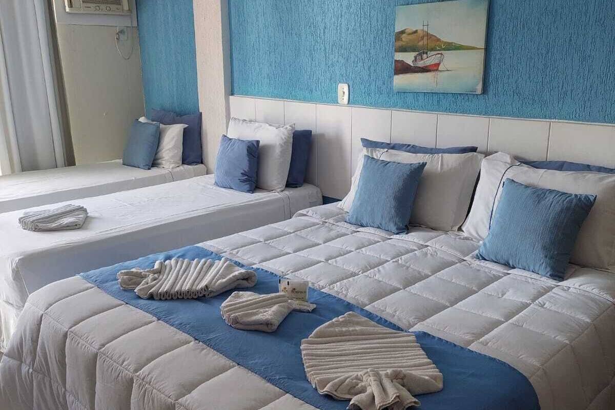 Ein Hotelzimmer mit zwei Betten, einem großen Gemälde und einem Fenster mit Vorhängen.