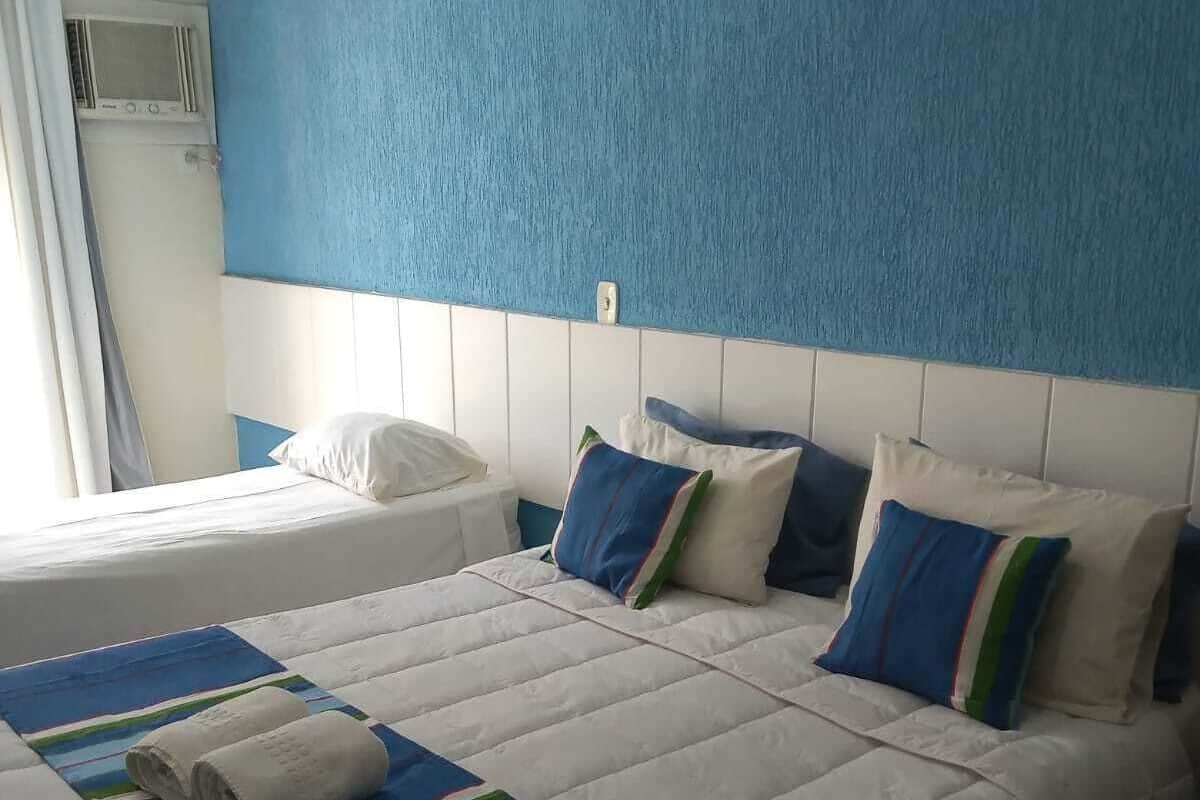 Ein Hotelzimmer mit zwei Betten, einer blauen Akzentwand und einem Fenster mit Vorhängen.