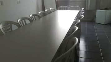 A conference room with a long table and chairs, a whiteboard, and a window with a view of buildings.