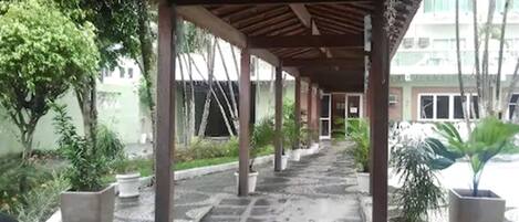 Un pasaje cubierto con plantas en macetas y suelo de piedra.