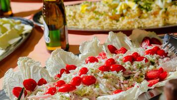 A table with a salad, a bottle, and a plate of food.