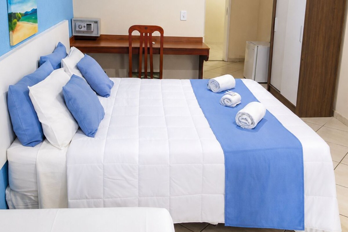 Una habitación de hotel con cama, escritorio, silla y armario.