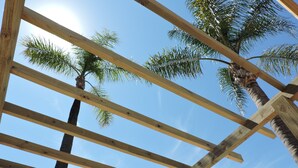 A wooden pergola structure with a clear blue sky and palm trees in the background. - Pousada Terra Sul (Porto Alegre)