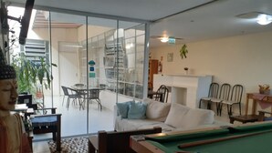 A room with a pool table, a sofa, a dining table with chairs, and a Buddha statue. - Pousada Terra Sul (Porto Alegre)