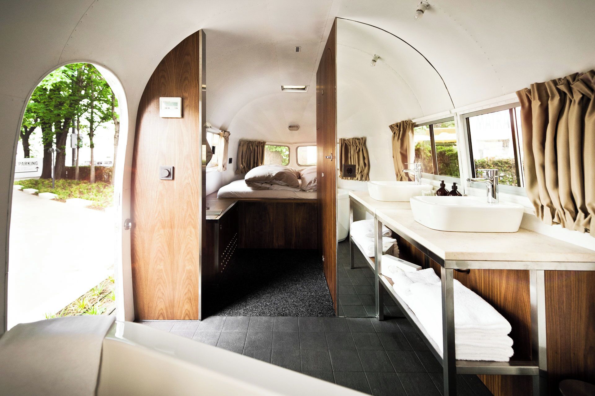 Ein kompaktes, modernes Wohnmobil-Interieur mit Bett, Spüle und Spiegel.