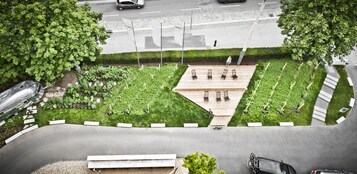 Um jardim no terraço com um deck de madeira, área de estar e vista para a rua.