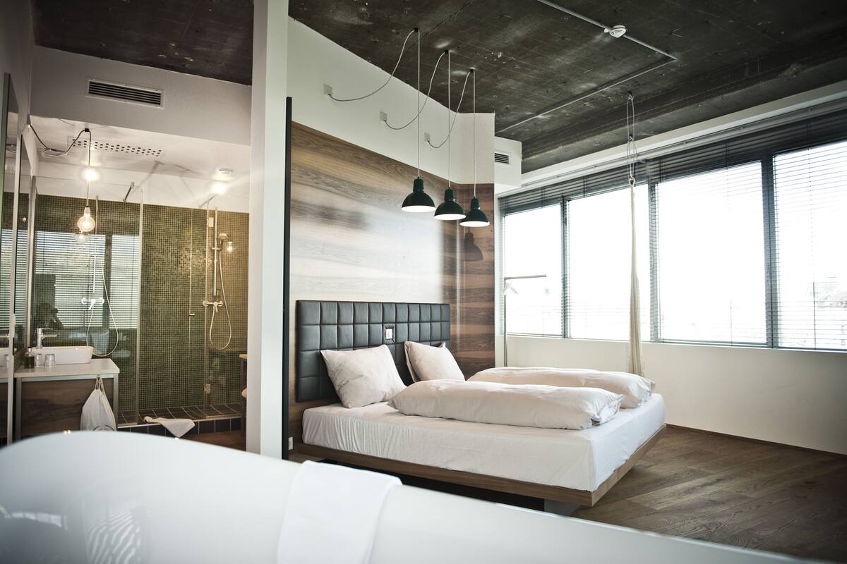 A modern bedroom with a large bed, a built-in vanity, and a large window.