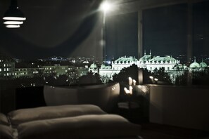 A room with a view of a cityscape at night, featuring illuminated buildings and a prominent dome structure.