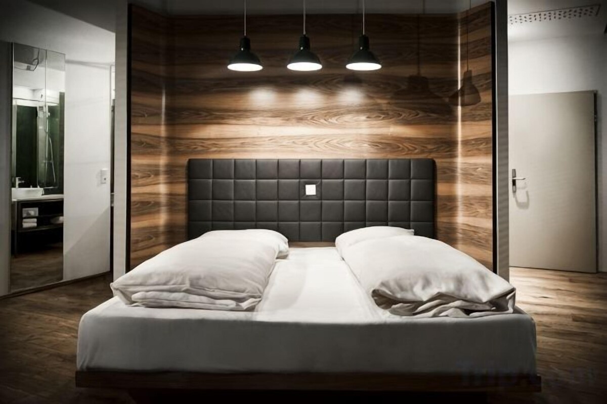 Un dormitorio con una cama, paneles de madera en la pared y tres lámparas colgantes.