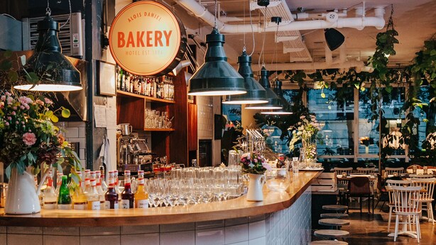 A bakery counter with a sign, bar area with stools, and a view of the street outside. - Hotel Daniel Vienna (Vienna)