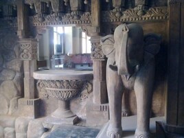 Una estatua de piedra de un elefante en una habitación con esculturas ornamentales y suelo de piedra.