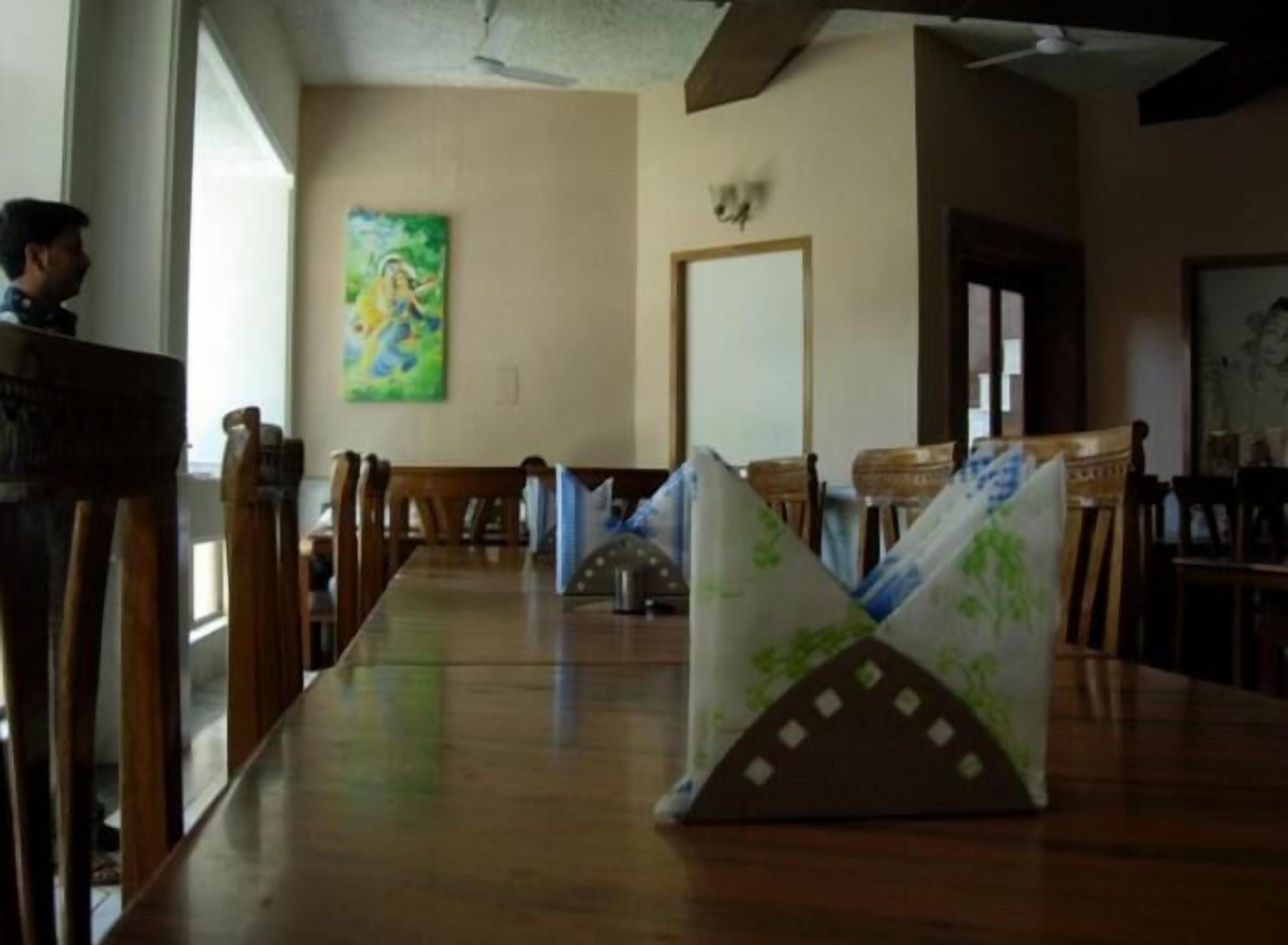 Una larga mesa de comedor con sillas, un cuadro en la pared y un ventilador de techo.