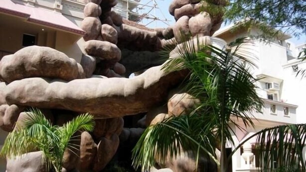 A rock formation with palm trees in front of a building. - Ananda Krishna Van (Mathura)