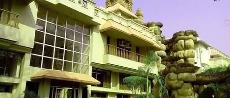 A hotel with a modern design, featuring a large windowed facade, a prominent tower, and a landscaped garden with a rock formation.