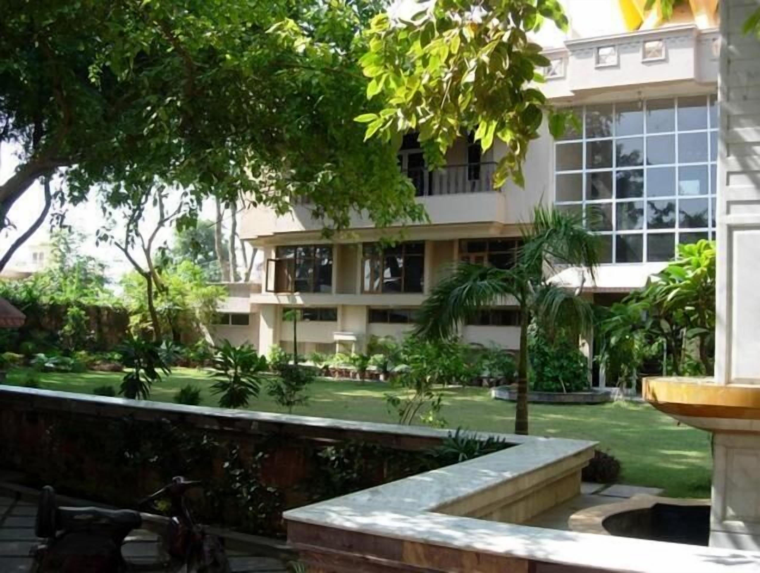 Un edificio de varios pisos con un patio interior ajardinado, una fuente y una estatua.