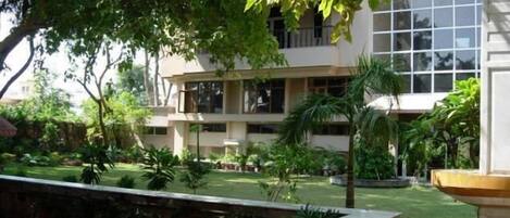 Un edificio de varios pisos con un patio interior ajardinado, una fuente y una estatua.