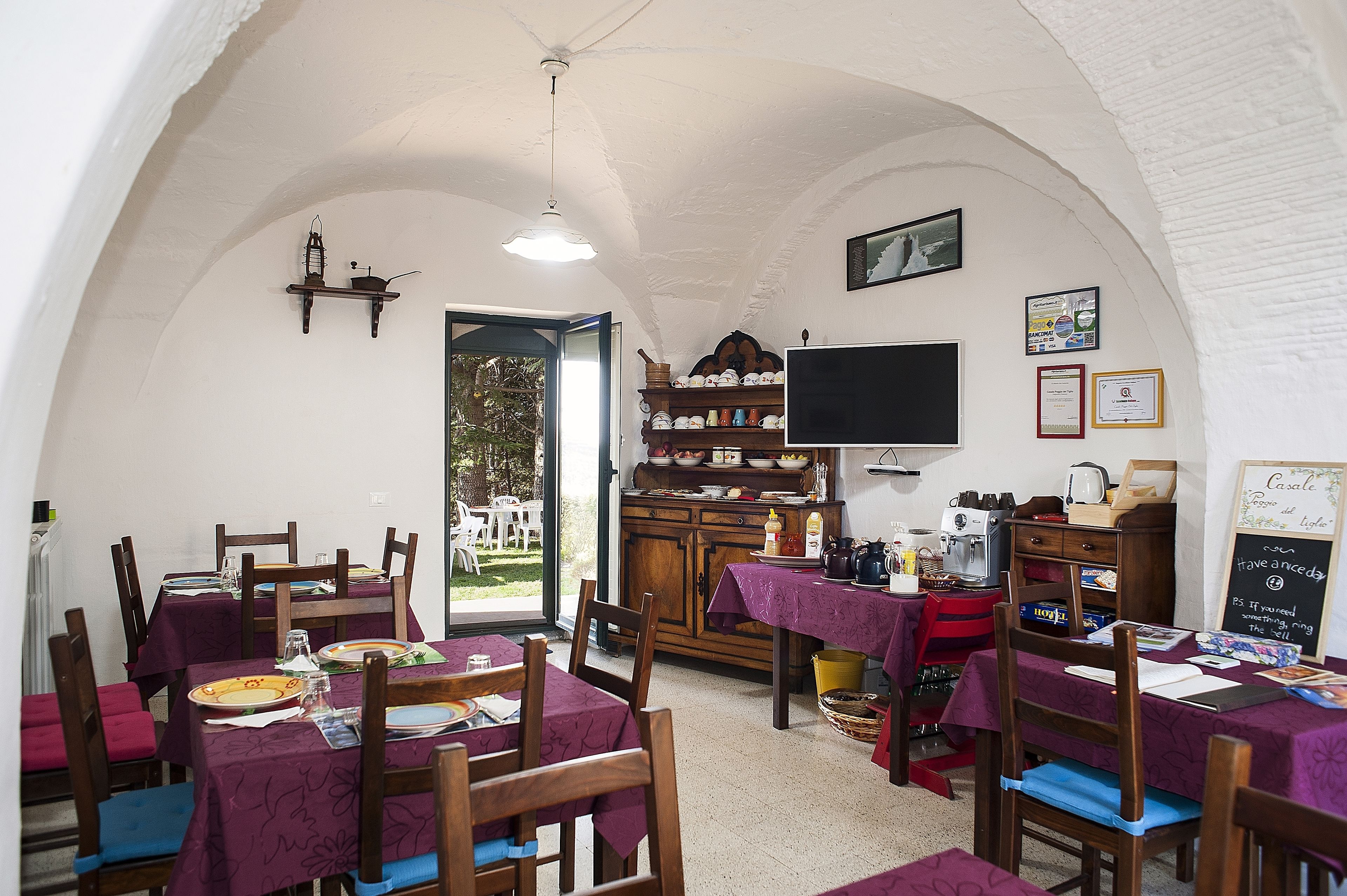 A dining area with tables set for meals, a television, and a chalkboard menu.