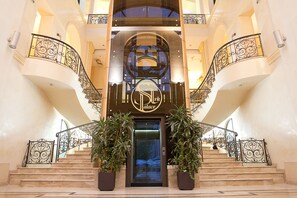 Una entrada imponente con una doble escalera, un letrero destacado y barandales de hierro decorativos.