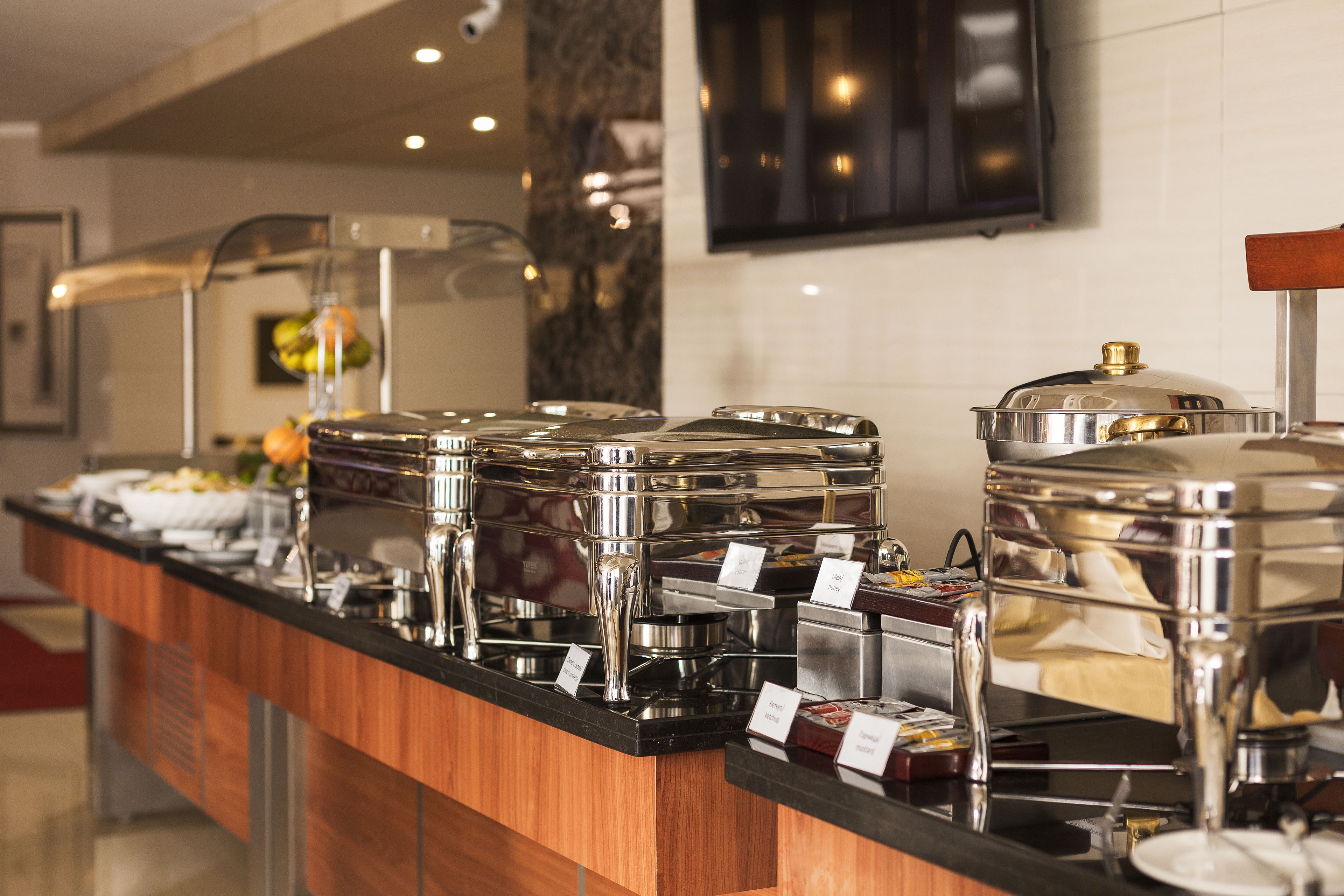 A buffet setup with multiple self-service stations, each with a metal container and a sign indicating the type of food.